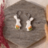 Handmodellierte Hasen Ohrringe aus weißem Polymerton mit roten Rosen und hypoallergenem Edelstahl-Verschluss auf Naturstein fotografiert