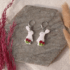 Handmodellierte Hasen Ohrringe aus weißem Polymerton mit roten Rosen und hypoallergenem Edelstahl-Verschluss auf Naturstein fotografiert